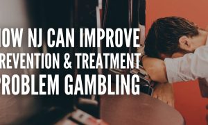 A man buries his head in his arms at a slot machine, representing an individual who suffers from a gambling problem. Experts believe New Jersey has done well addressing the issue, but more can always be done.