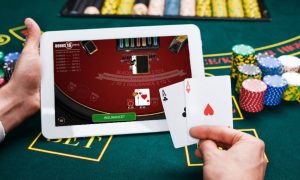 man plays betmgm double up blackjack on ipad while holding cards