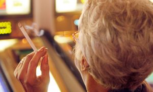 Woman plays slots while smoking for a story on the New Jersey Senate health committee discusses banning smoking at Atlantic City casinos