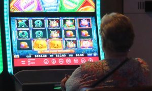 Woman plays slots at Harrah's Atlantic City for a story on January 2024 revenue reports for online casinos in New Jersey, NJ sports betting and Atlantic City casinos