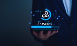 Image of a man holding a mobile device with an updating logo for a story on Caesars Palace Online Casino installing major upgrades to its New Jersey platform.