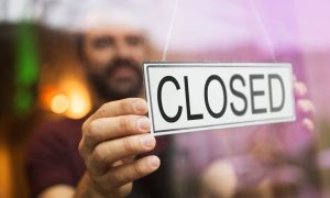 A man hands a closed sign in a window for a story on Prophet Exchange shutting down its New Jersey sports betting platform.