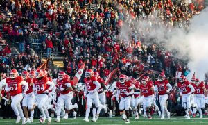 Rutgers football team runs onto field for a story on a bill that would allow New Jersey sportsbooks to accept bets on in-state college sports.