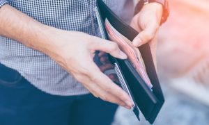 a man opens up a wallet full of currency