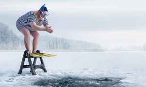 Freezing cold winter day man prepares to dive into ice water