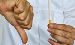a person holding a cigarette with a thumbs down