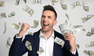 a man celebrates while hundred dollar bills fall around him