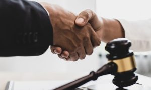 two hands shaking next to a gavel