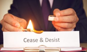 a man lighting a cease and desist sign on fire